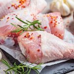 Raw chicken legs on slate with spice containing bird, board, and chicken